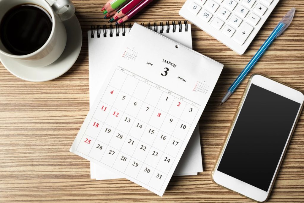 Calendario de escritorio con smartphone, calculadora y café.