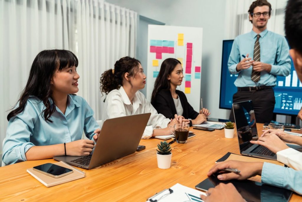 Equipo de trabajo en reunión analizando información con laptops y presentación.
